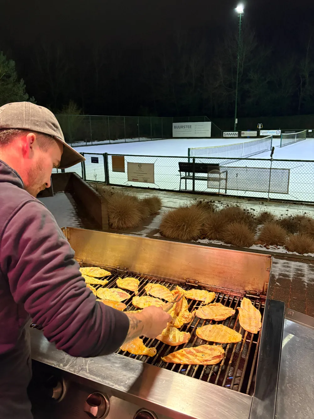 Onze chef bakt gemarineerde kipfilet op de gasbarbecue tijdens een winteravond