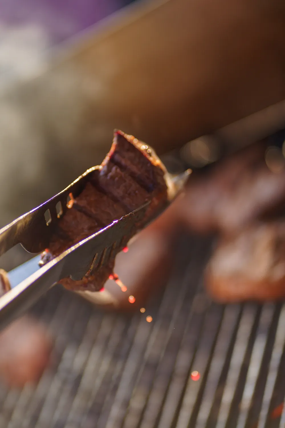 Chef keert een biefstuk op de grill met een tang